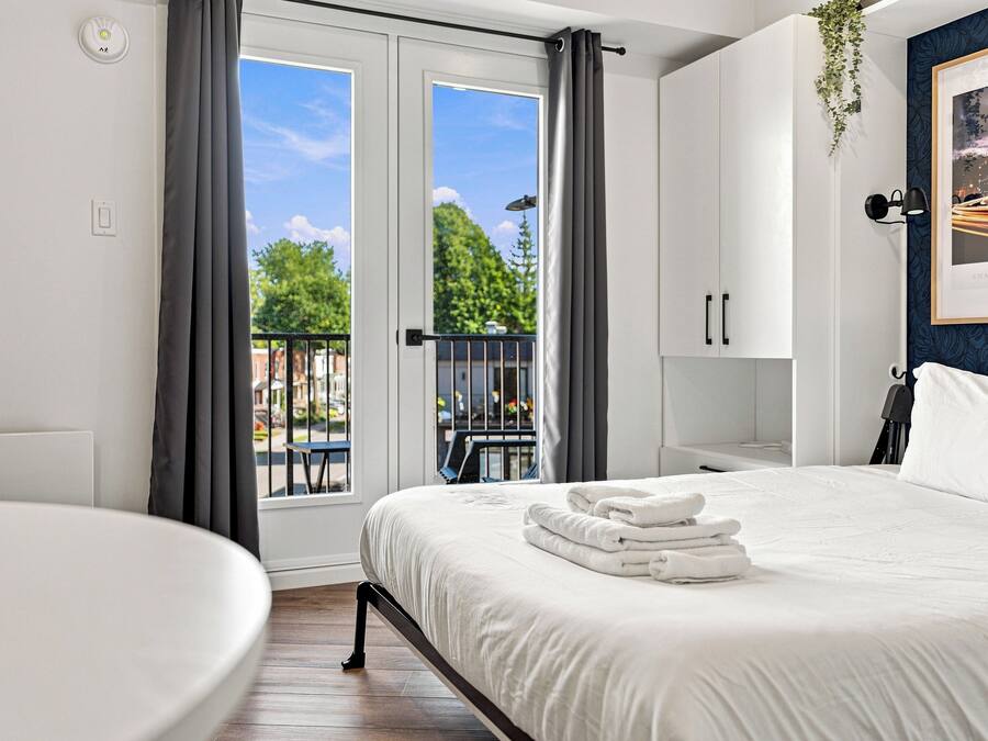 A hotel room with a bed, a chair, a balcony, and a view of the outdoors.