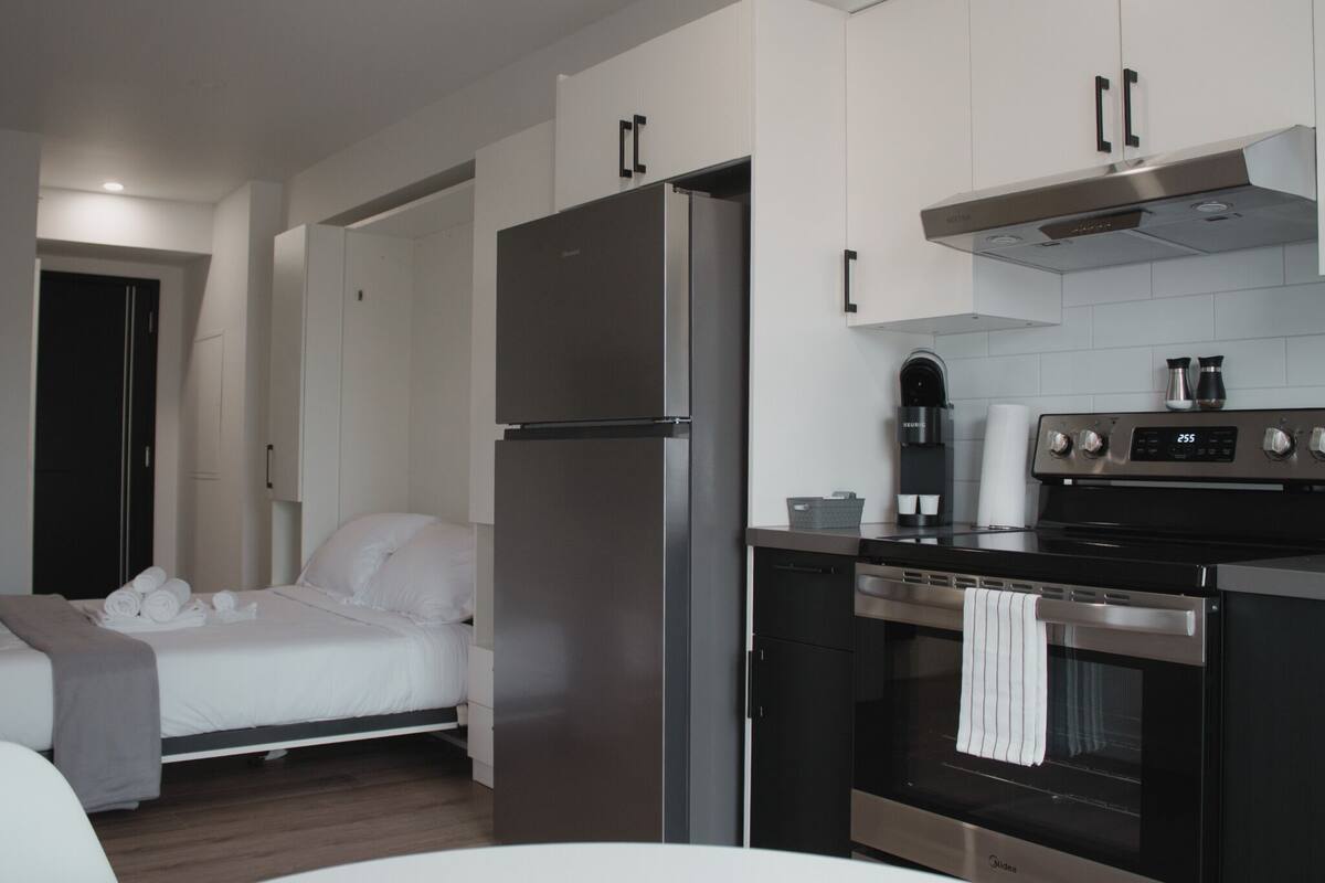 A compact kitchen with a refrigerator, oven, and coffee maker.