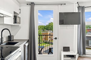 Una cocina moderna con microondas integrado, un hervidor negro y un lavamanos de acero inoxidable.