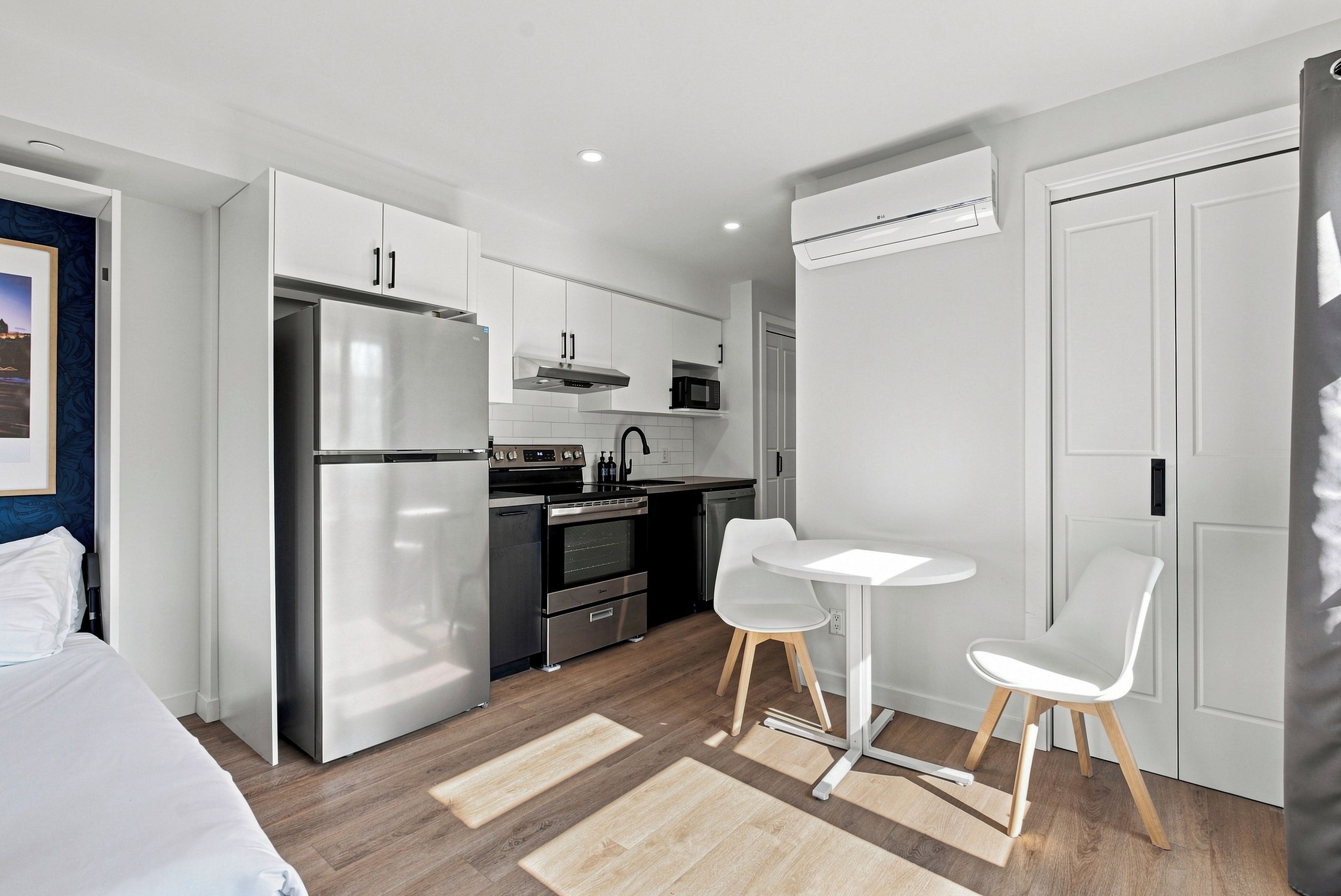 Una cocina moderna con refrigerador, estufa, microondas y un pequeño comedor con dos sillas.