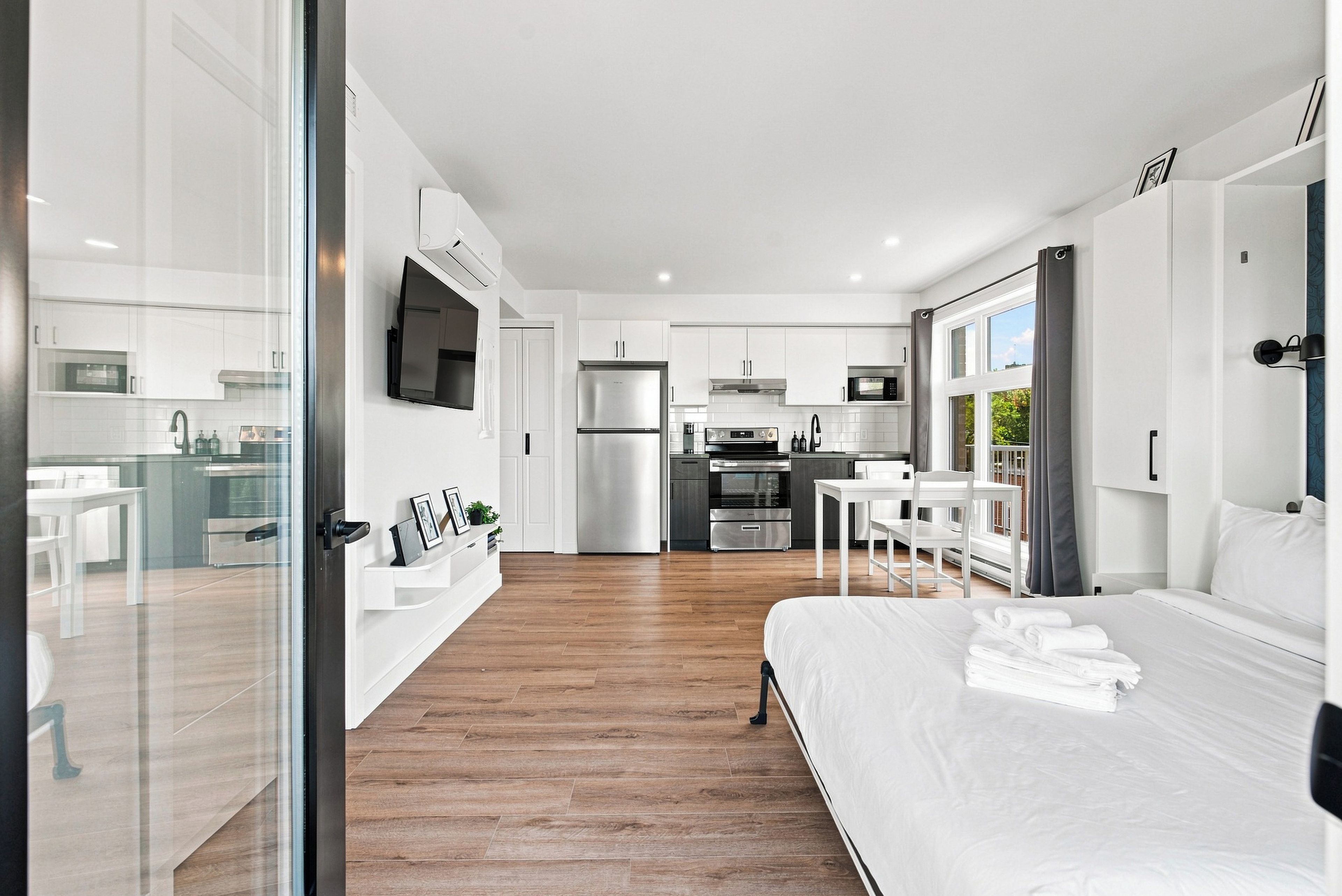 Una habitación de hotel moderna con una cama grande, un comedor, una cocina y una sala de estar.