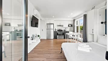 Una habitación de hotel moderna con una cama grande, un comedor, una cocina y una sala de estar.