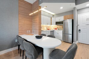 A modern kitchen with white cabinets, a stainless steel refrigerator, and a central island with chairs. - Magical Mickey Retreat, Free Shuttle, Free Parking (Orlando)