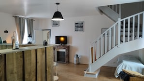 Eine moderne Küche mit Holzbalken, Kamin, Fernseher und einer Treppe.