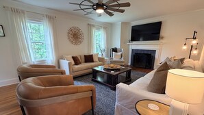 A living room with a sofa, armchair, coffee table, fireplace, and a ceiling fan.