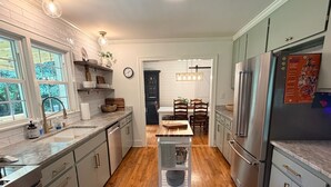A modern kitchen with a central island, stainless steel appliances, and a dining area with wooden chairs.