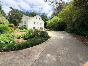 Una casa de dos pisos con jardín delantero y entrada para vehículos.