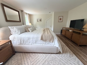 Une chambre à coucher avec un grand lit, une commode en bois, une télévision et un miroir.