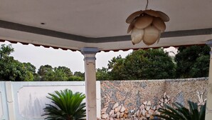 Un patio cubierto con mesa y sillas, un muro decorativo y vistas a la vegetación circundante.