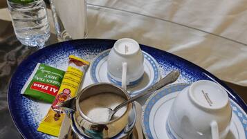 A tray with a teapot, two cups, a bottle of water, and a packet of green tea.