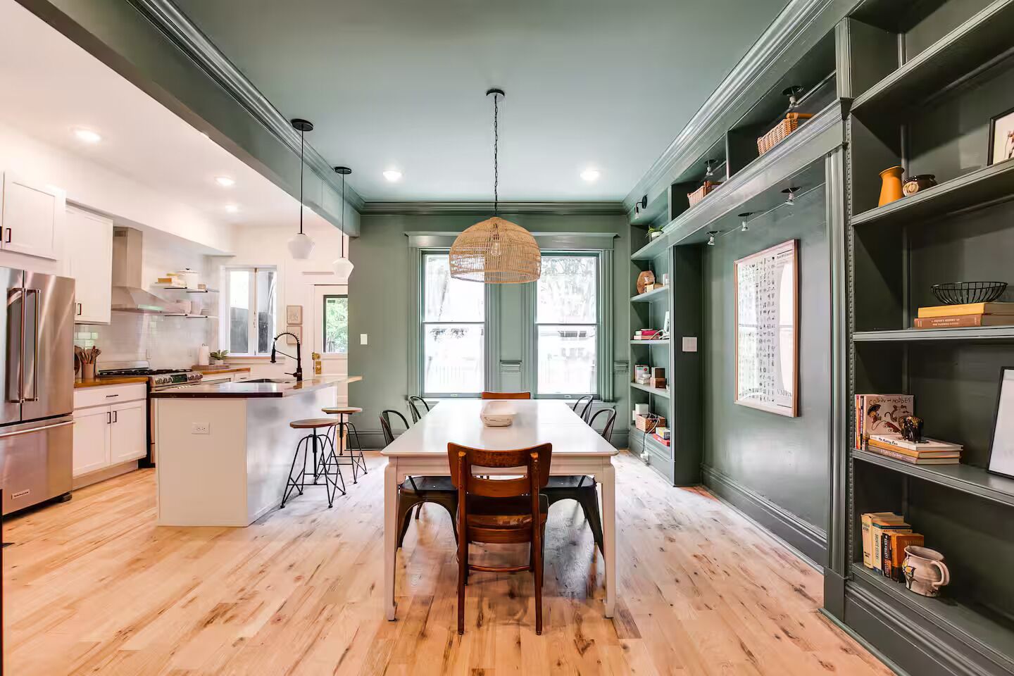 Una cocina moderna con una isla central, taburetes de bar y una mesa de comedor.