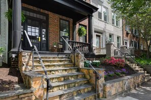 Un edificio residencial con una escalera de piedra, una puerta negra y fachada de ladrillo.