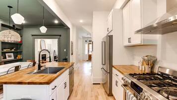 Una cocina moderna con una isla central, electrodomésticos de acero inoxidable y encimera de madera.