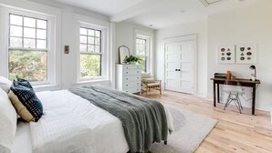 A bedroom with a large bed, a desk, a chair, and a wardrobe.