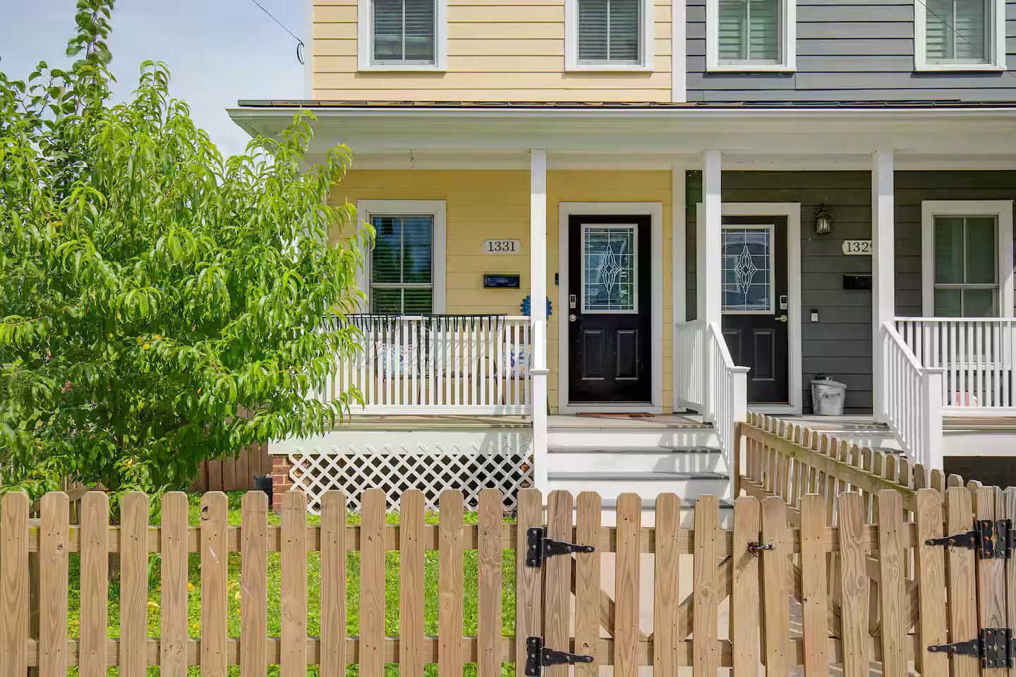 A two-story house with a porch, a black front door, and a mailbox.