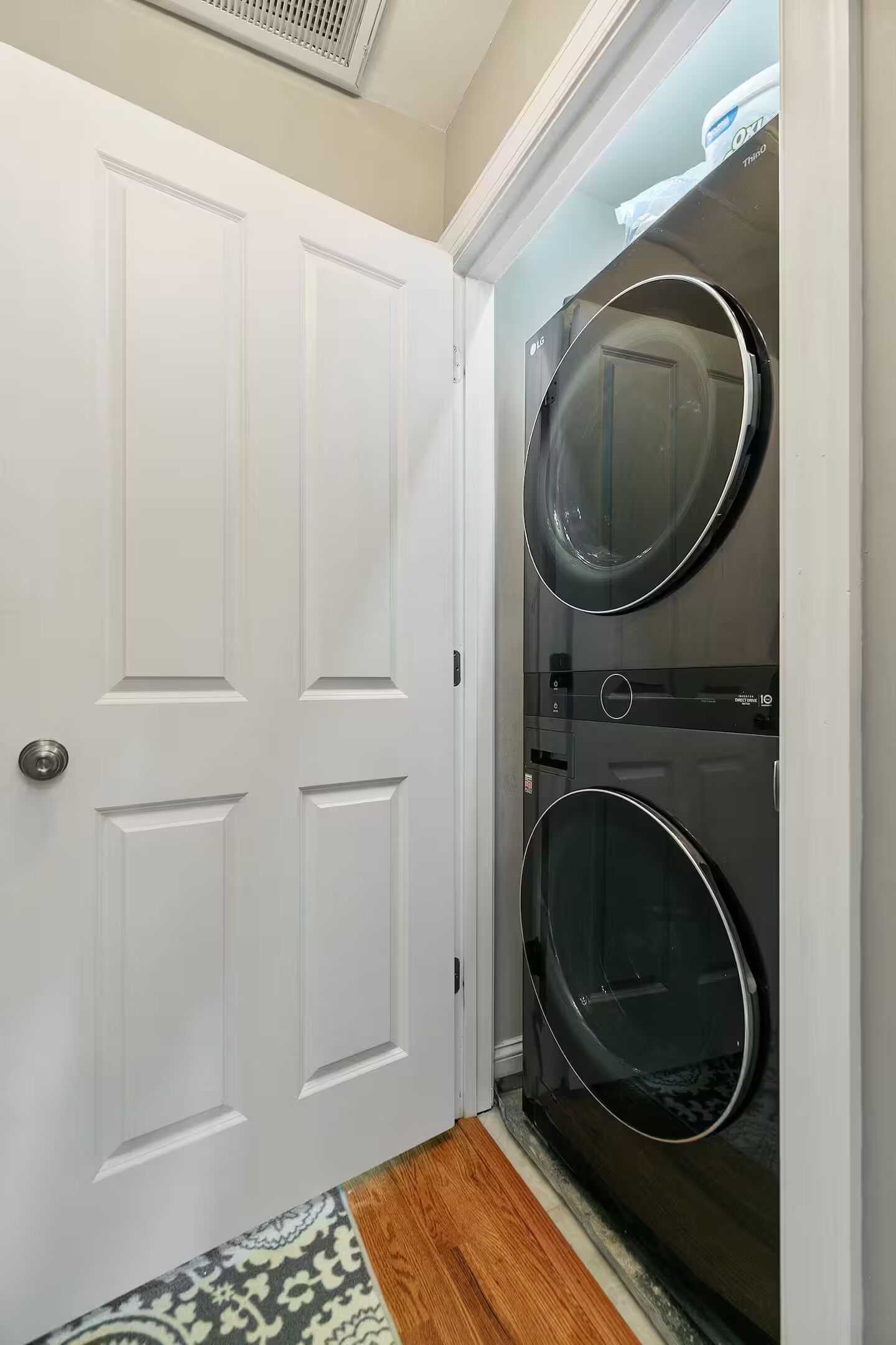 Une buanderie équipée de deux machines à laver à chargement frontal, d’une porte blanche et d’un tapis à motifs.
