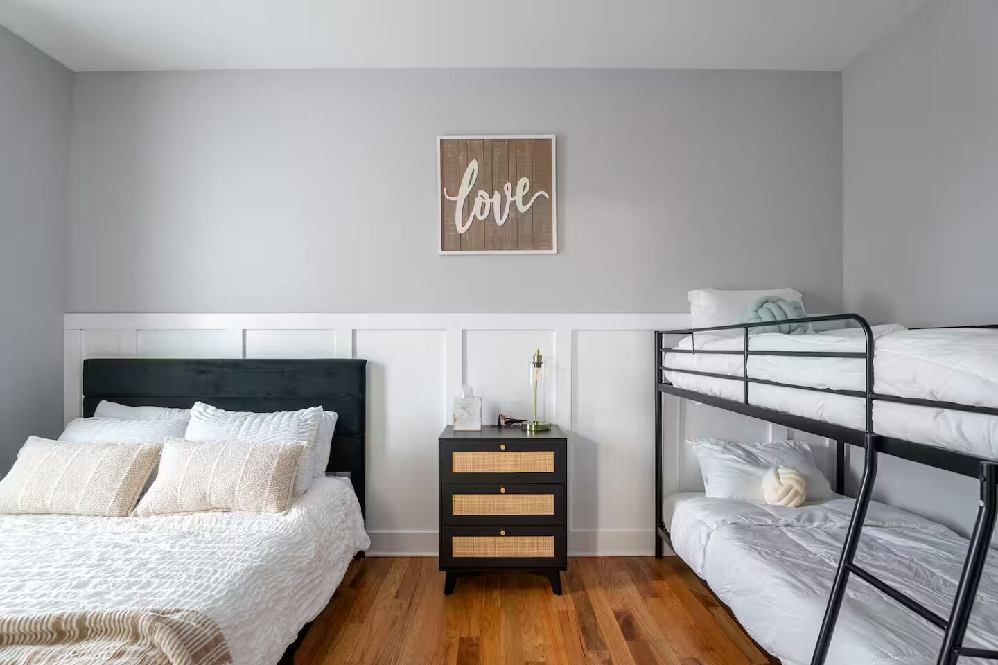 Ein Schlafzimmer mit Etagenbett, einem Einzelbett, einem Nachttisch mit Lampe und einer Wand mit der Aufschrift 'love'.