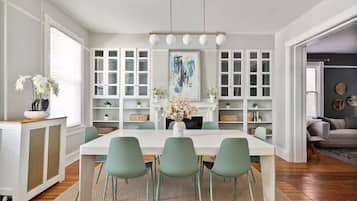 Une salle à manger moderne avec une table blanche, des chaises vertes et un lustre.
