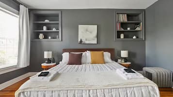 Une chambre d’hôtel moderne avec un grand lit, des tables de chevet, une bibliothèque et une fenêtre avec des rideaux.
