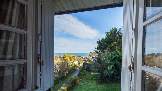 An open window with a view of a coastal village, greenery, and a clear sky. - Family home with sea view: garden & beach nearby (Ploubazlanec)