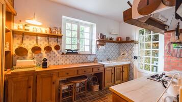 Une cuisine avec des meubles en bois, une fenêtre, un évier et des casseroles suspendues.