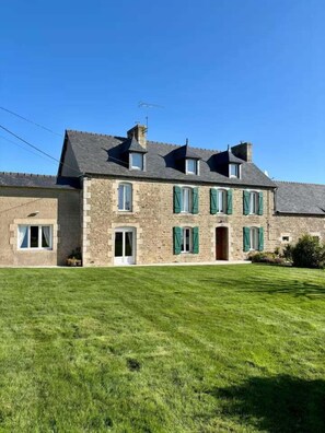 Un bâtiment en pierre doté de nombreuses fenêtres et d’une grande pelouse à l’avant.