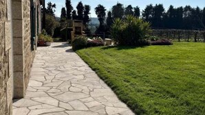 A stone pathway leading to a grassy area with a building on the left. - Breton longhouse with garden in Trédaniel (Trédaniel)