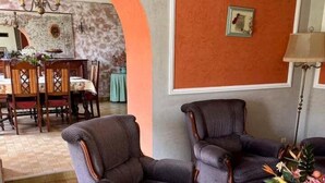 A living room with two armchairs, a dining table with chairs, a chandelier, and a wall-mounted picture. - Breton longhouse with garden in Trédaniel (Trédaniel)
