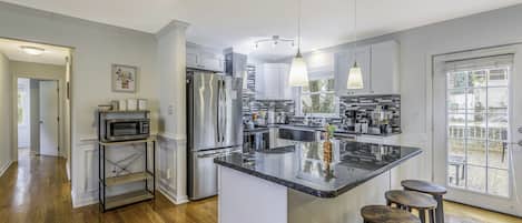 Uma cozinha moderna com uma ilha central, eletrodomésticos de aço inoxidável e um espaço com banquetas.