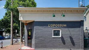 Een gebouw met een bord waarop 'L'OPOSSUM' staat en een klein raam.