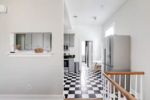 A modern kitchen with grey cabinets, a black and white checkered floor, and a stainless steel refrigerator. - Walk to Allianz Urban Oasis in Oregon Hill (Richmond)