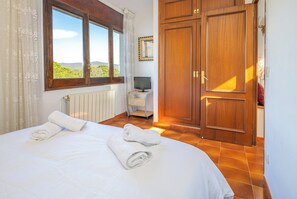 Ein Schlafzimmer mit Bett, Fenster, Fernseher und Kleiderschrank.