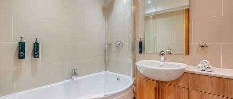 Un baño moderno con una bañera independiente, un lavabo y un espejo encima.