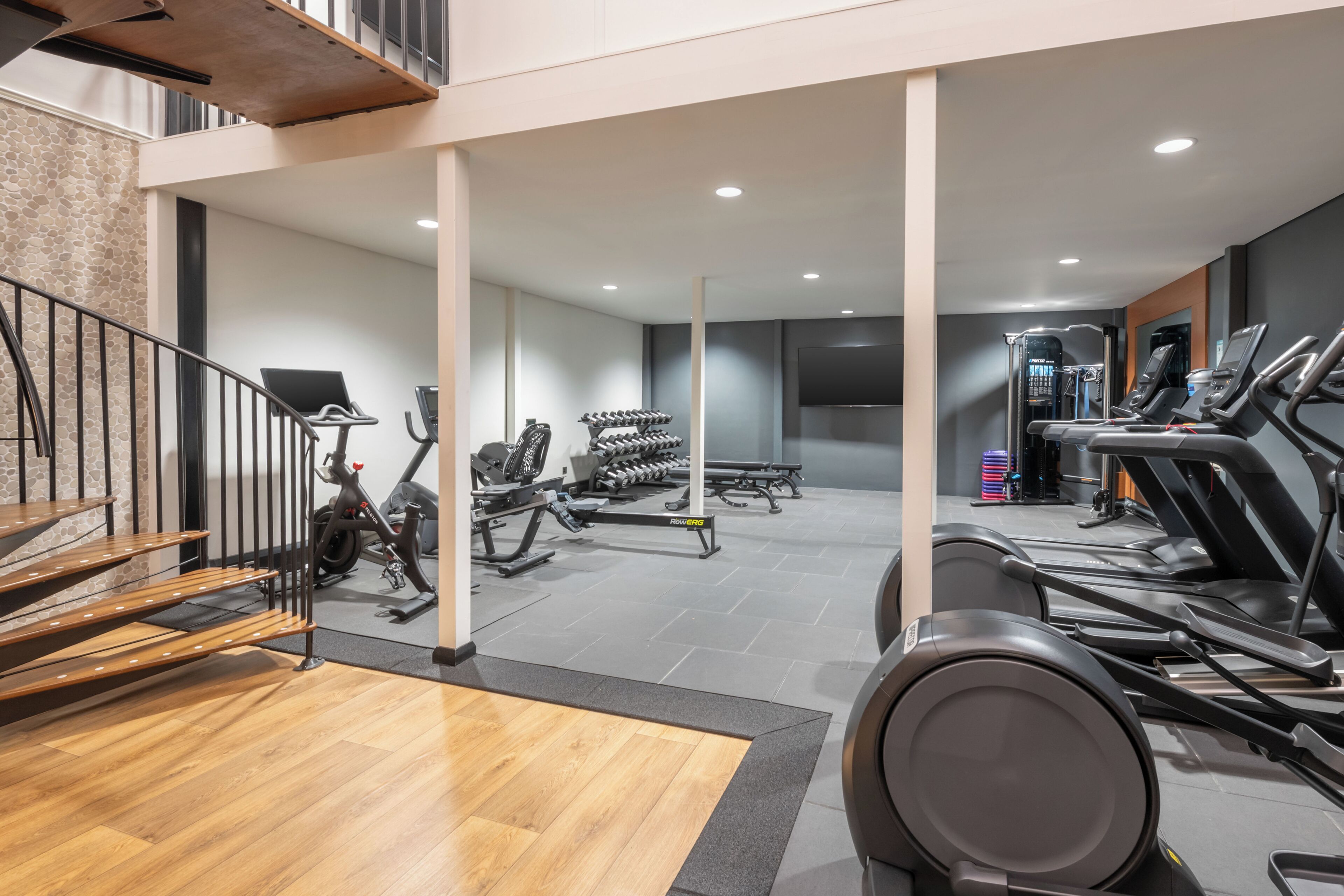 Un gimnasio con cintas de correr, elípticas y máquinas de pesas.