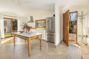 Eine moderne Küche mit Holztisch, Edelstahlgeräten und einer Glastür zum Garten.