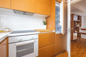 Eine Küche mit weißen Schränken, einer Arbeitsplatte, einem Herd und einem offenen Kühlschrank.