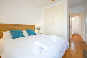 Ein Hotelzimmer mit Bett, Kissen, Nachttisch, Lampe, Kleiderschrank und einem Gang.