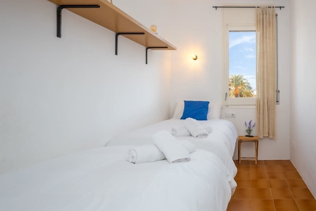 Ein Hotelzimmer mit einem Bett, einem Nachttisch, einem Fenster mit Vorhängen und einer Wandleuchte.