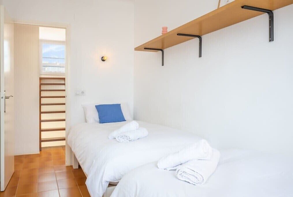 Un dormitorio con dos camas, una estantería de madera y una ventana con persianas.