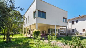 Et moderne hus med to etager, en overdækket terrasse, en have og en lille pool.