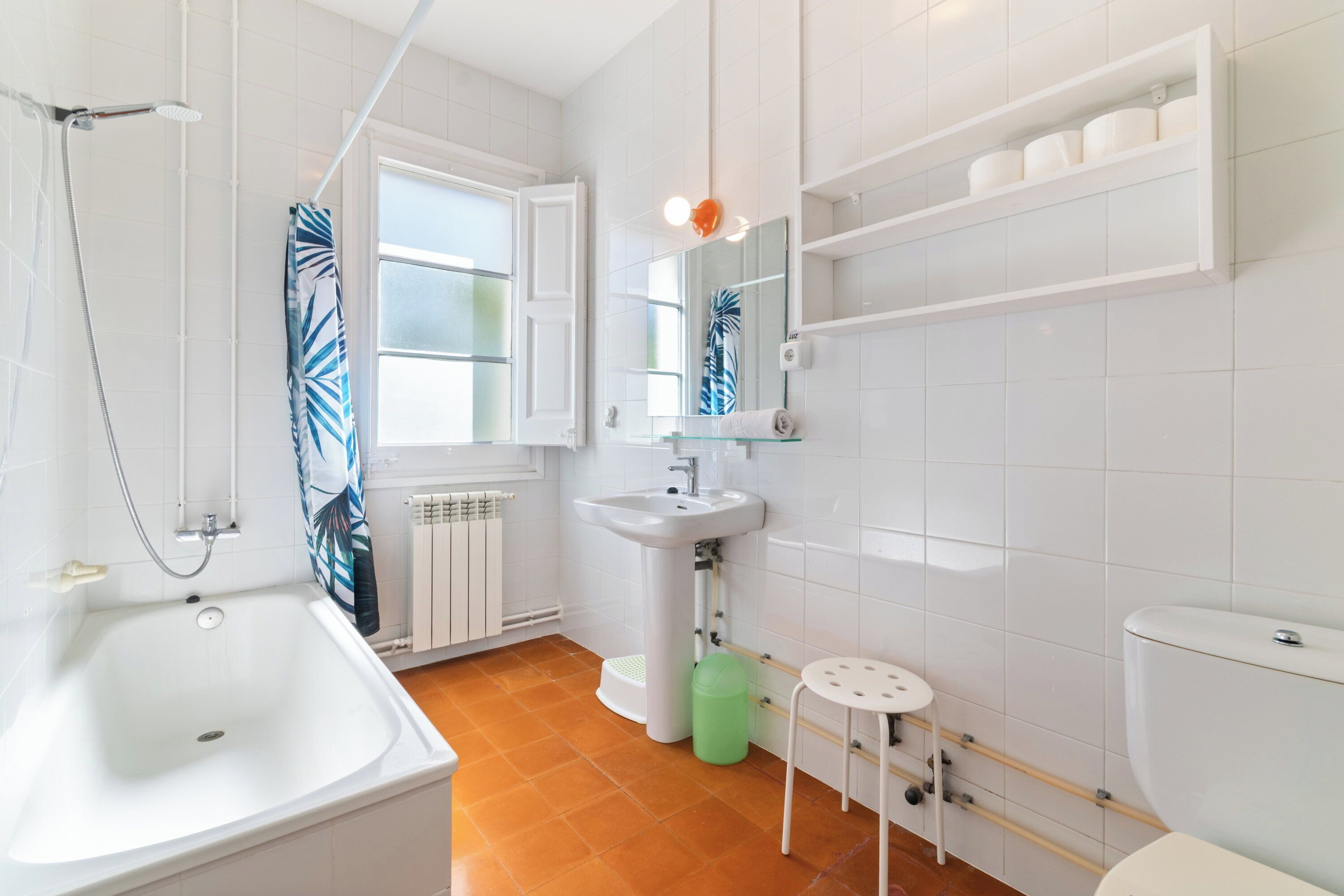 A bathroom with a bathtub, sink, toilet, and a window with a view.