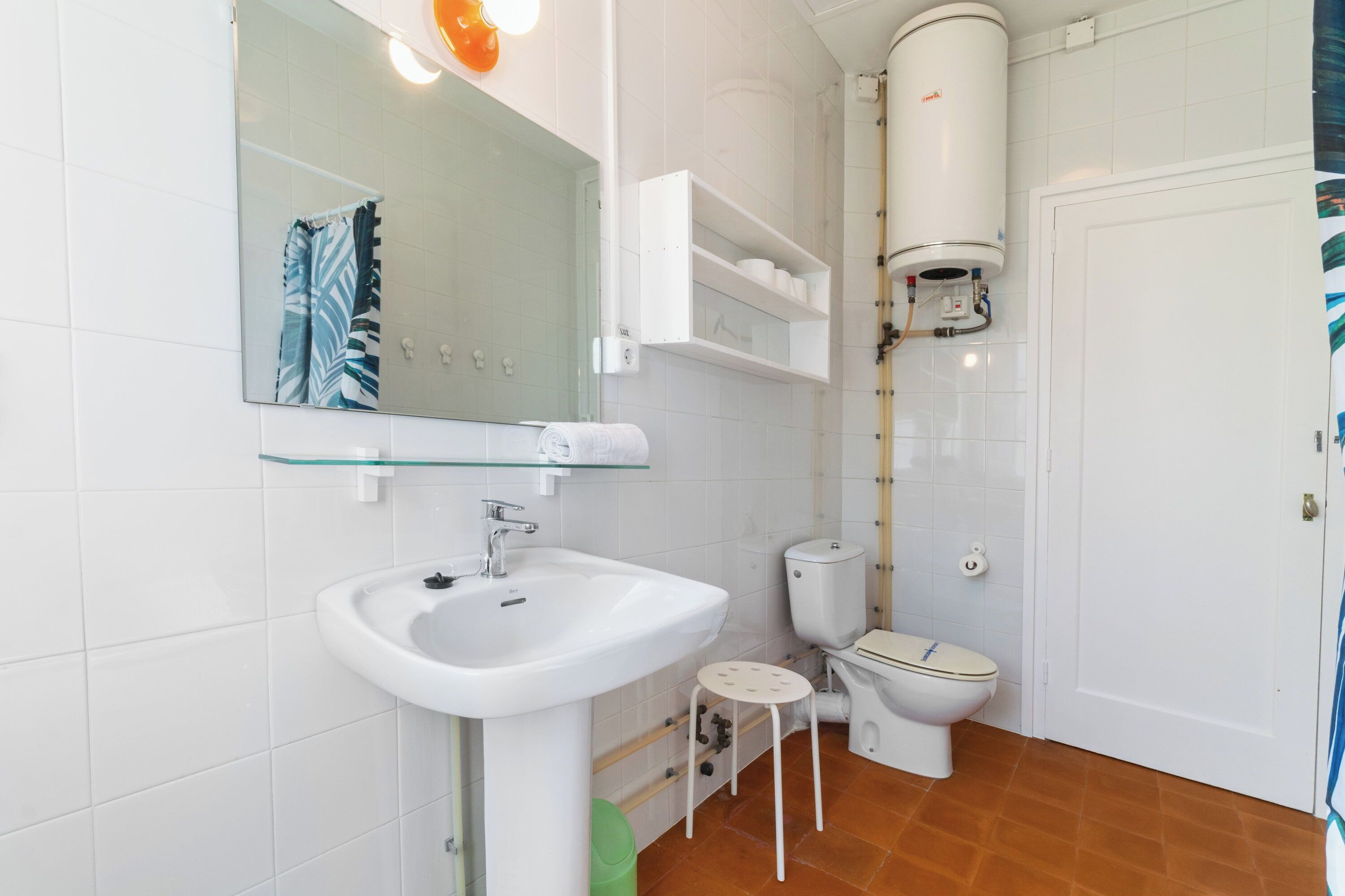 A bathroom with a white sink, a toilet, a mirror, and a towel rack.
