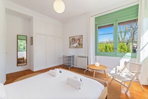 Ein Hotelzimmer mit Bett, einem kleinen Tisch, einem Stuhl, einer Heizung, einem Fenster mit Blick und einem Bild an der Wand.