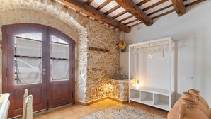 A rustic room with a stone wall, wooden door, tiled floor, and a white wardrobe. - Casa con patio, piedra y luz natural (Sant Pere de Ribes)