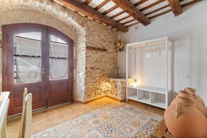 Ein rustikaler Raum mit Steinwand, Holztür, Fliesenboden und einem weißen Kleiderschrank.