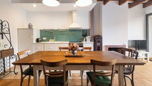 A spacious kitchen with a wooden table, chairs, and a brick fireplace. - Casa con patio, piedra y luz natural (Sant Pere de Ribes)
