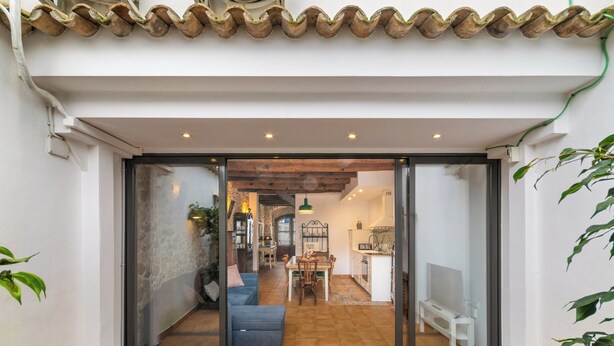 A modern interior with a dining area, kitchen, and a cozy seating space. - Casa con patio, piedra y luz natural (Sant Pere de Ribes)