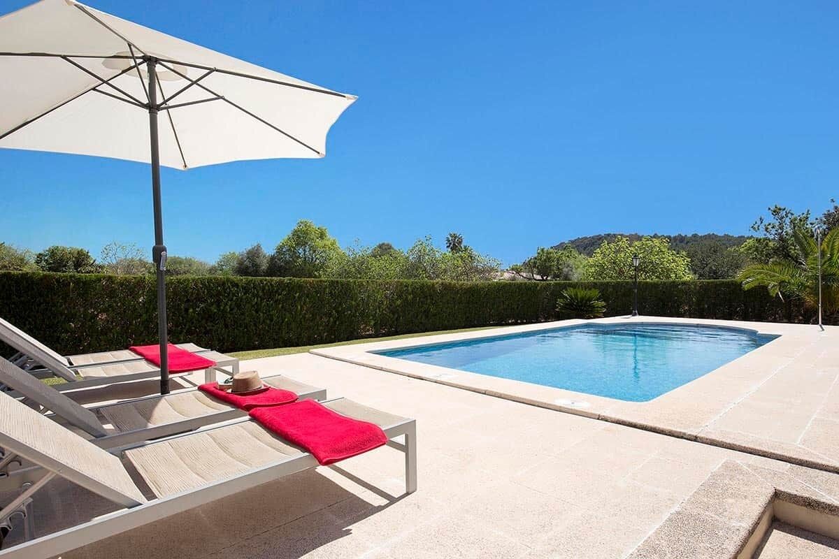 Una piscina con lettini e un ombrellone.