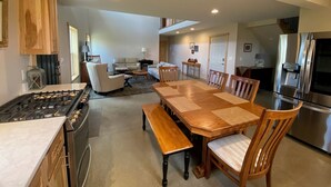 Una cocina moderna con estufa a gas, una mesa de comedor de madera, sillas y un refrigerador.