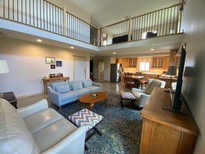 A spacious living area with a sofa, armchairs, a coffee table, and a TV.